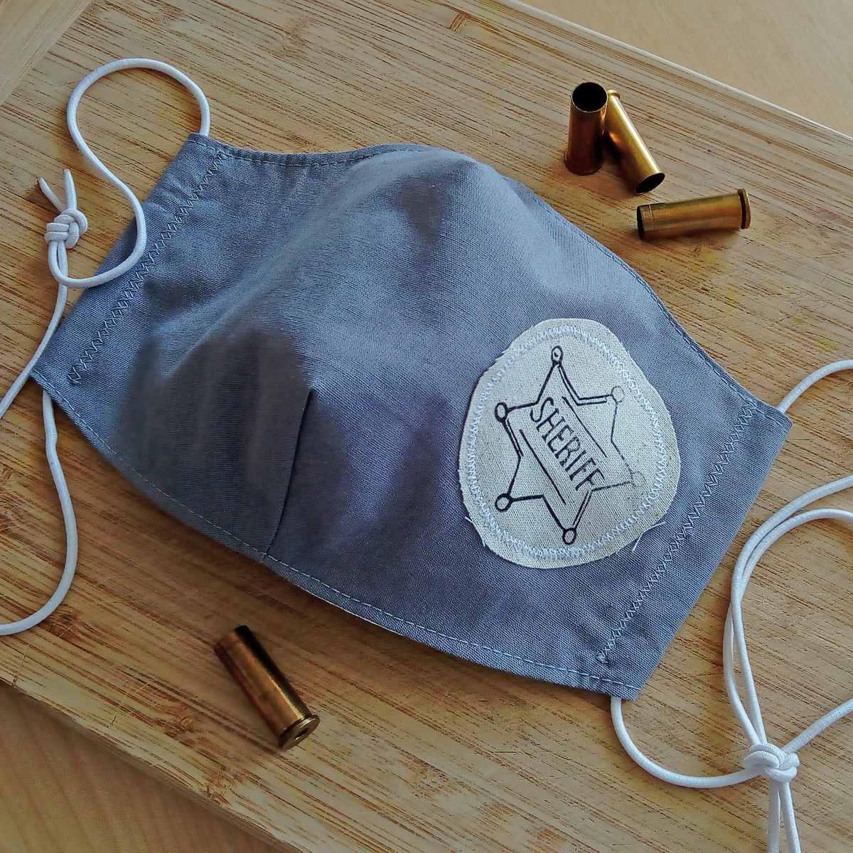 Světle šedá rouška s šerifskou hvězdou