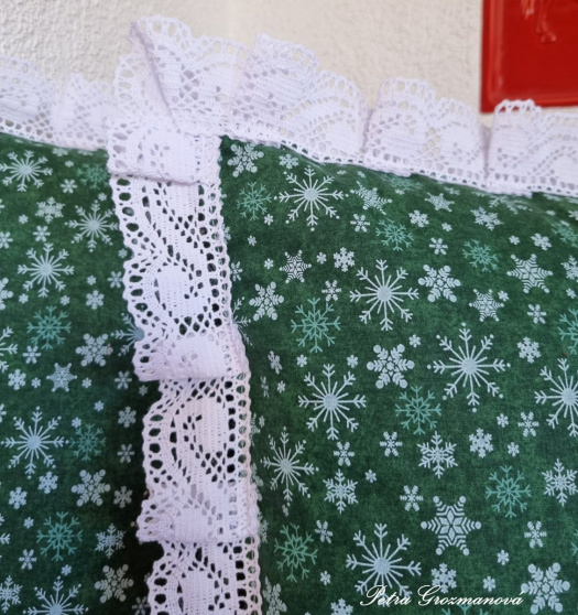 Vánoční polštář s motivem vloček, lemovaný krajkou šíře 45 mm, včetně výplně.