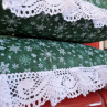 Vánoční polštář s motivem vloček, lemovaný krajkou šíře 45 mm, včetně výplně.