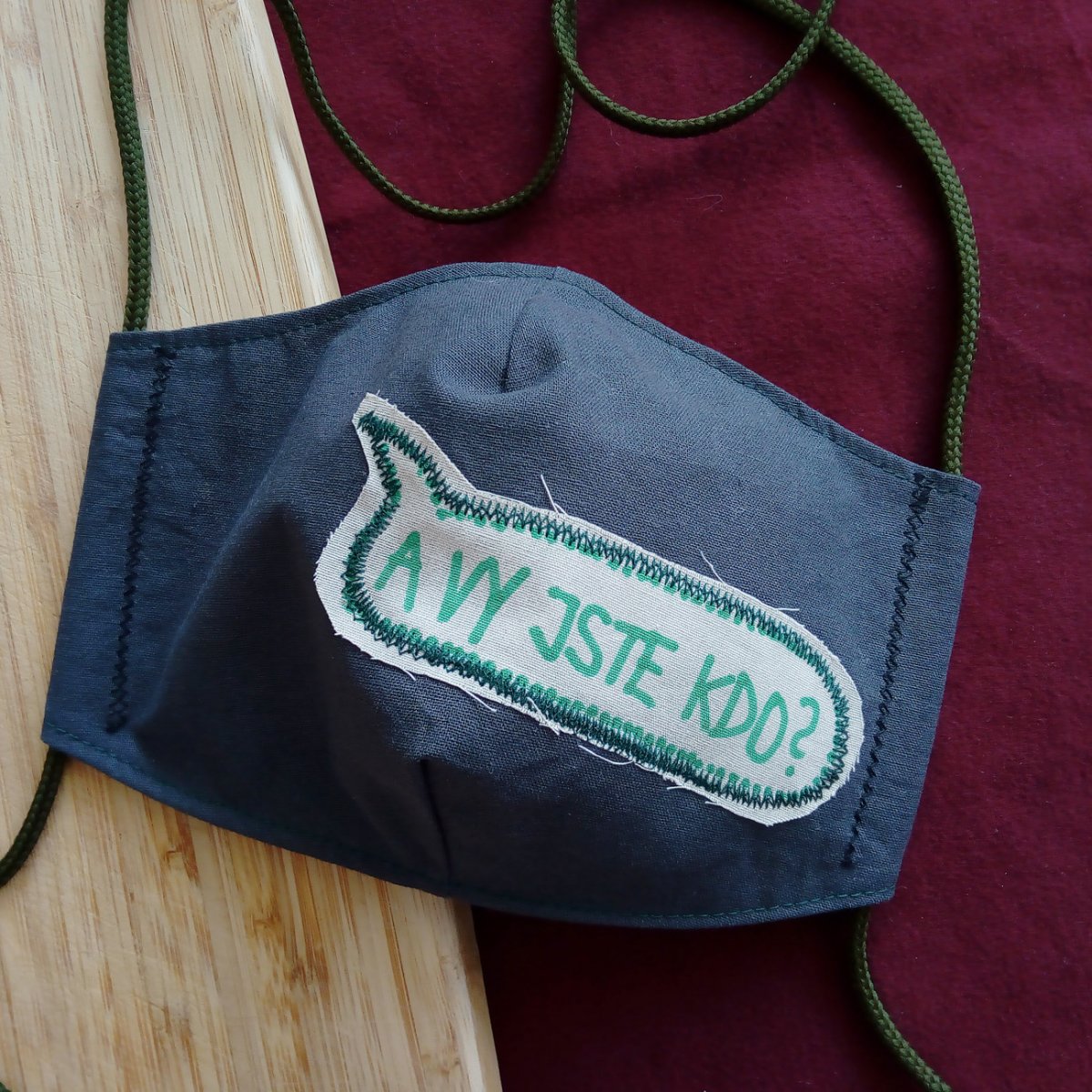 Šedá rouška s nápisem A vy jste kdo