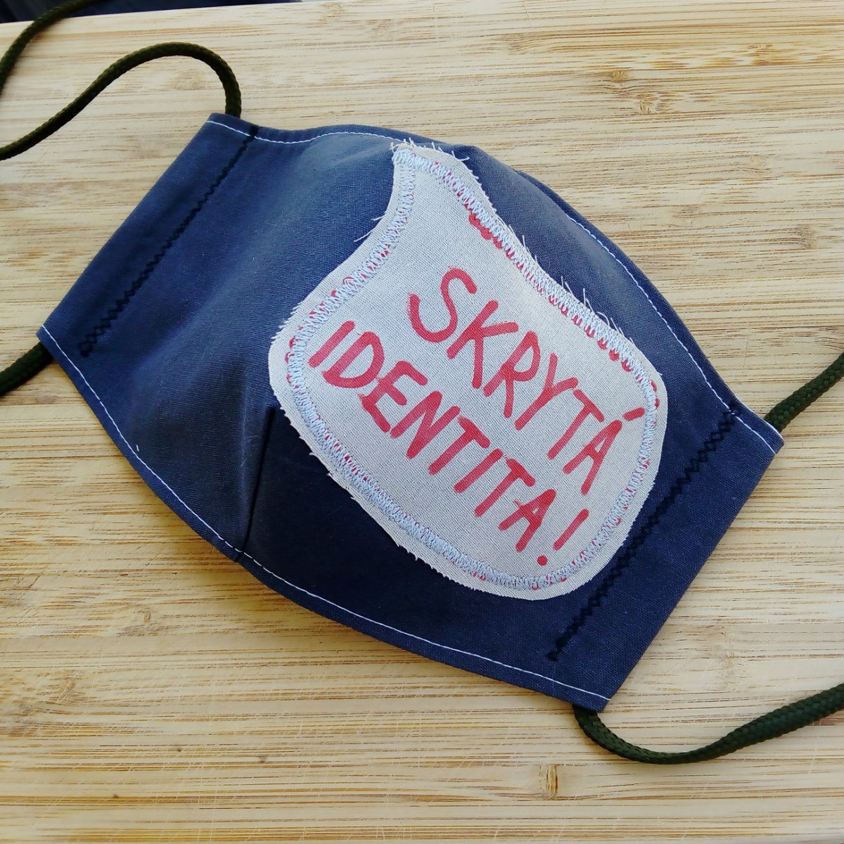 Šedá rouška s nápisem Skrytá identita