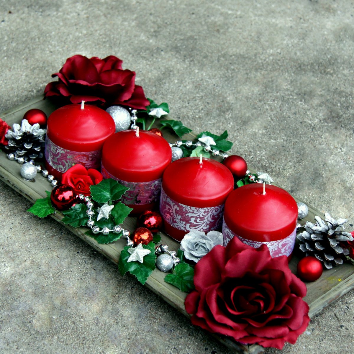 Vánoční svícen s vínovými růžemi na dřevěném tácu