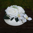 Kytice bílých růží a orchidejí na bílém keramickém polštáři