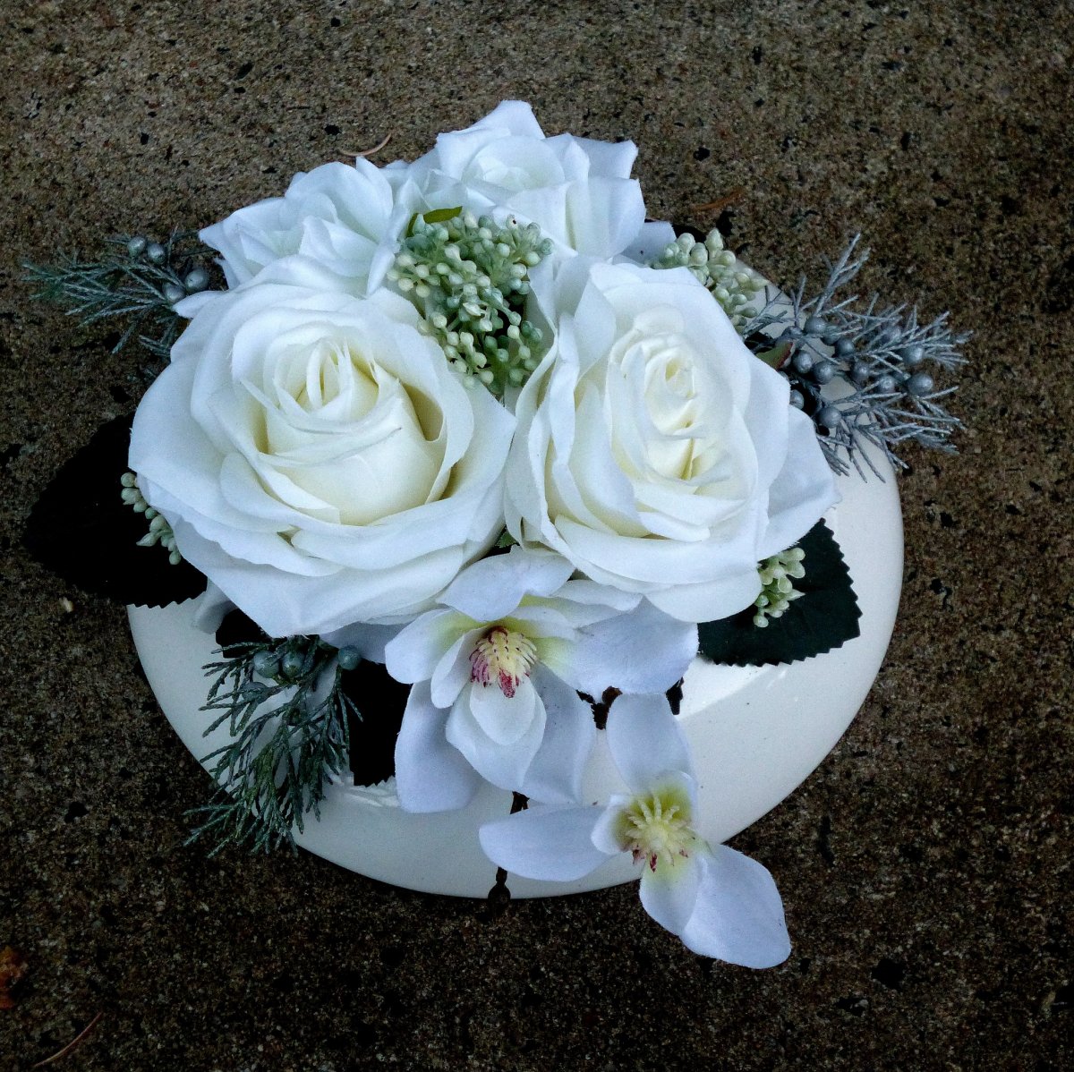 Kytice bílých růží a orchidejí na bílém keramickém polštáři