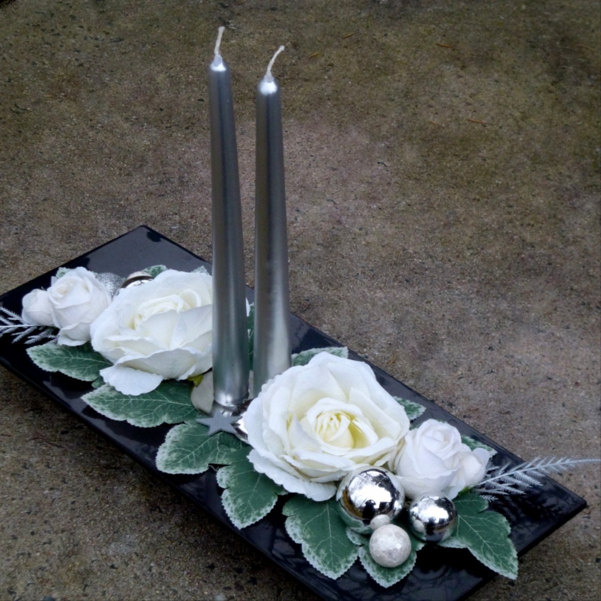 Svícen s bílými růžemi na černé lesklé misce