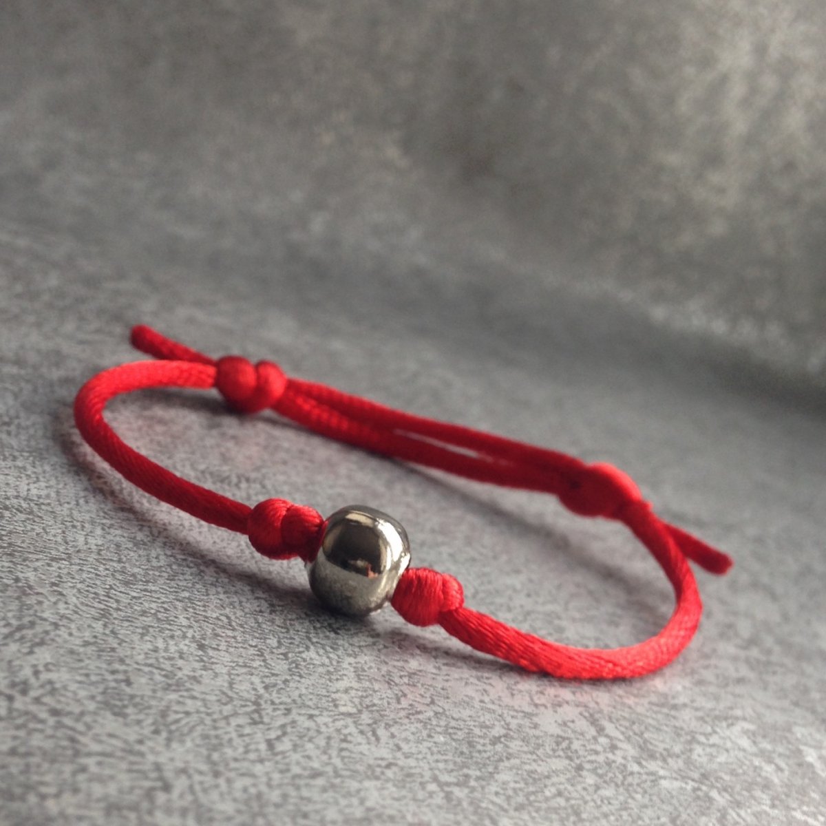 Červený náramek s kovovou kuličkou