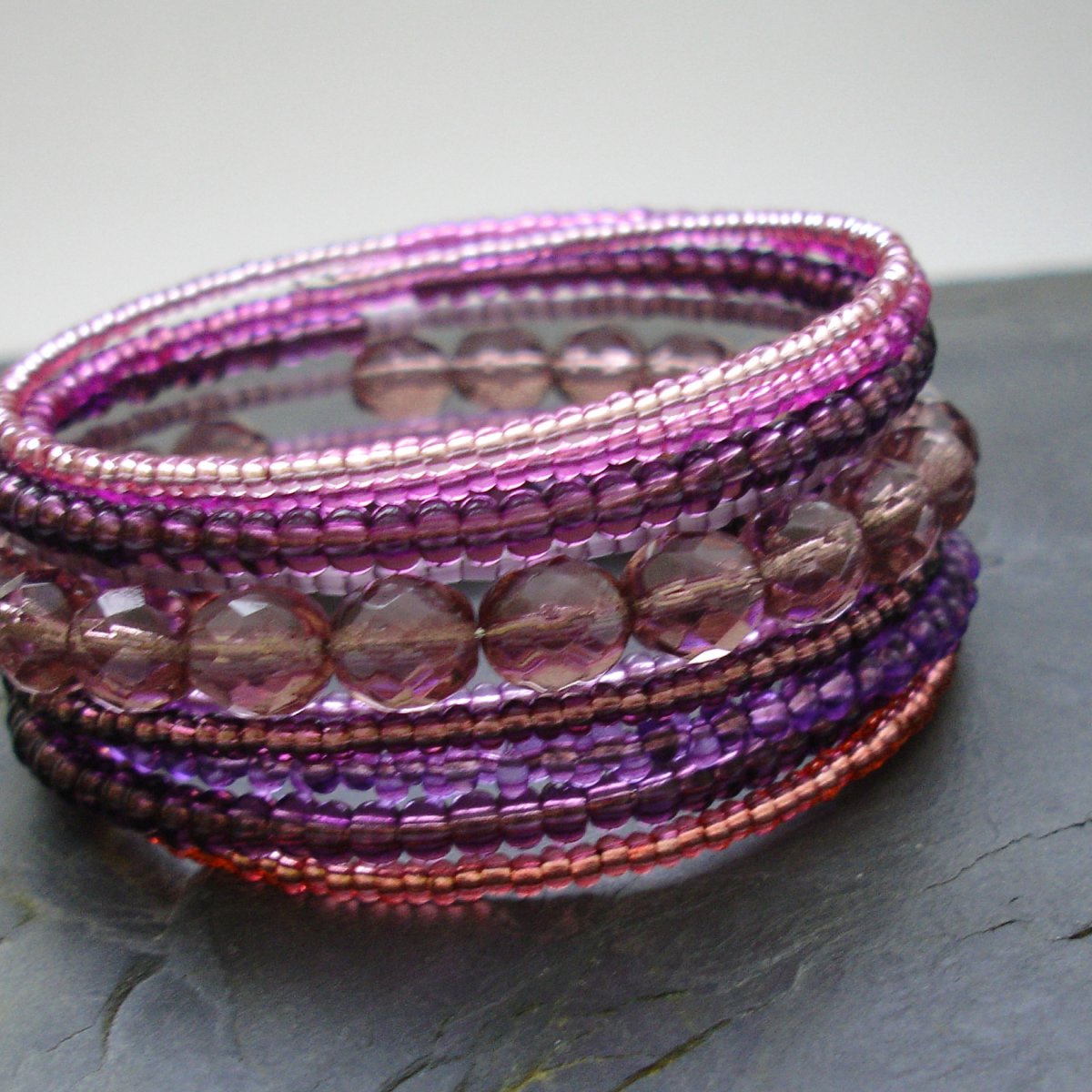 Skleněné a voskované korálky navlečené na  paměťovém drátu o průměru 6 cm.