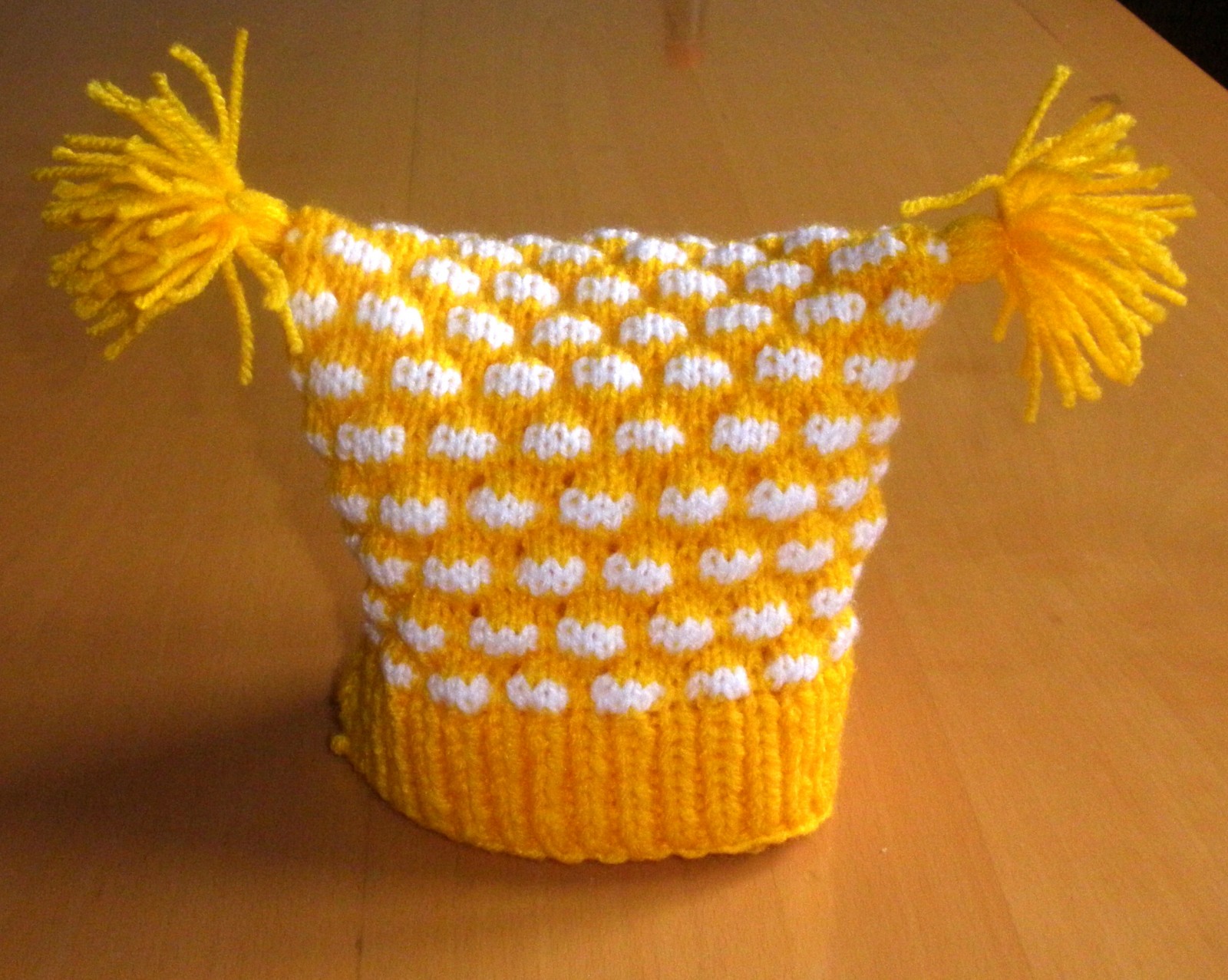 žlutobílá čepička se střapci